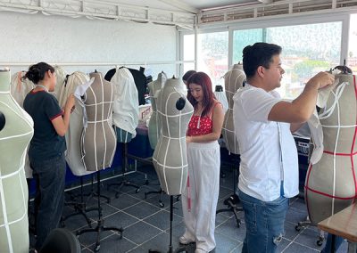 Se muestran varios alumnos creando prendas para la materia de modelado sobre maniquí.