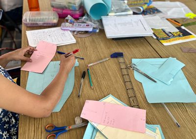 En esta imagen se ven alumnas en la clase de graduación de moldes. Ellas están creando patrones utilizando papel y marcadores.