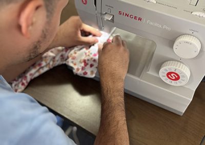 Alumnos aprendiendo a cose usando una máquina de coser marca singer en la clase de corte y confección.