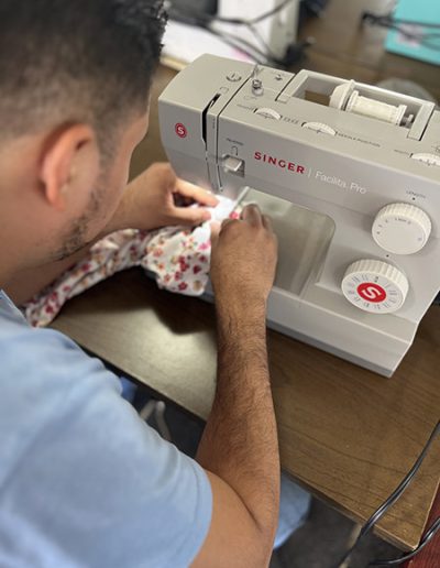 Alumnos aprendiendo a cose usando una máquina de coser marca singer en la clase de corte y confección.