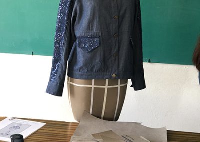 Creación de una prenda para la clase de producción industrial. Blusa de mezclilla azul de mangas largas con adornos en las mismas con las bolsas en la parte frontal inferior de la prenda.