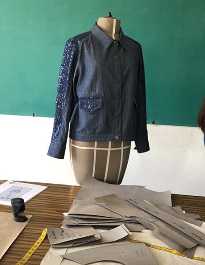 Creación de una prenda para la clase de producción industrial. Blusa de mezclilla azul de mangas largas con adornos en las mismas con las bolsas en la parte frontal inferior de la prenda.